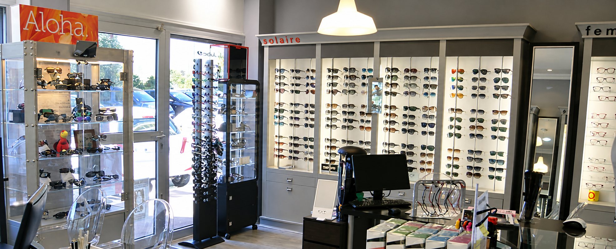 Intérieur lumineux d'un magasin d'optique avec des vitrines et des murs remplis de lunettes de soleil et de lunettes de vue.