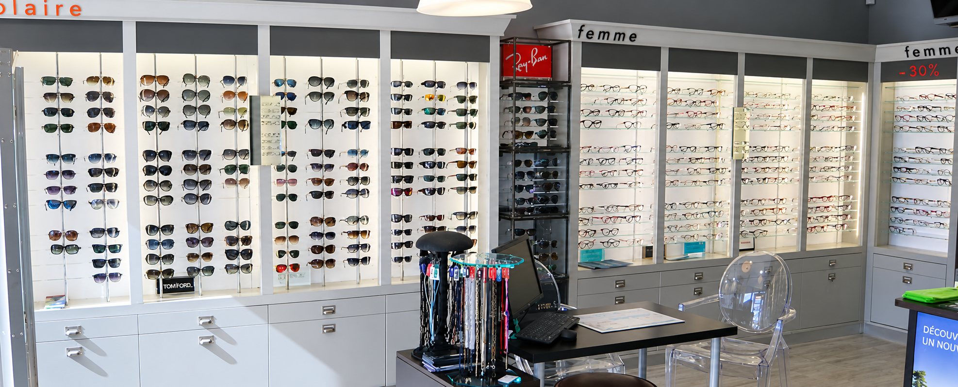 Intérieur lumineux d'une boutique d'optique avec des murs de lunettes de soleil et de vue, un comptoir noir et une chaise transparente.